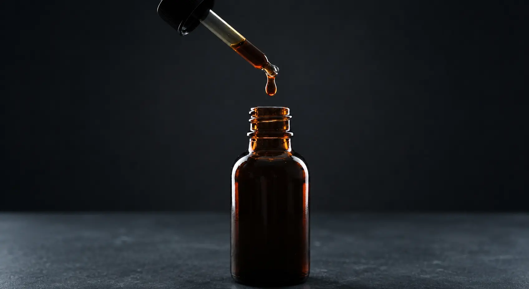 Amber propolis tincture bottle with a dropper, a single drop suspended above the opening